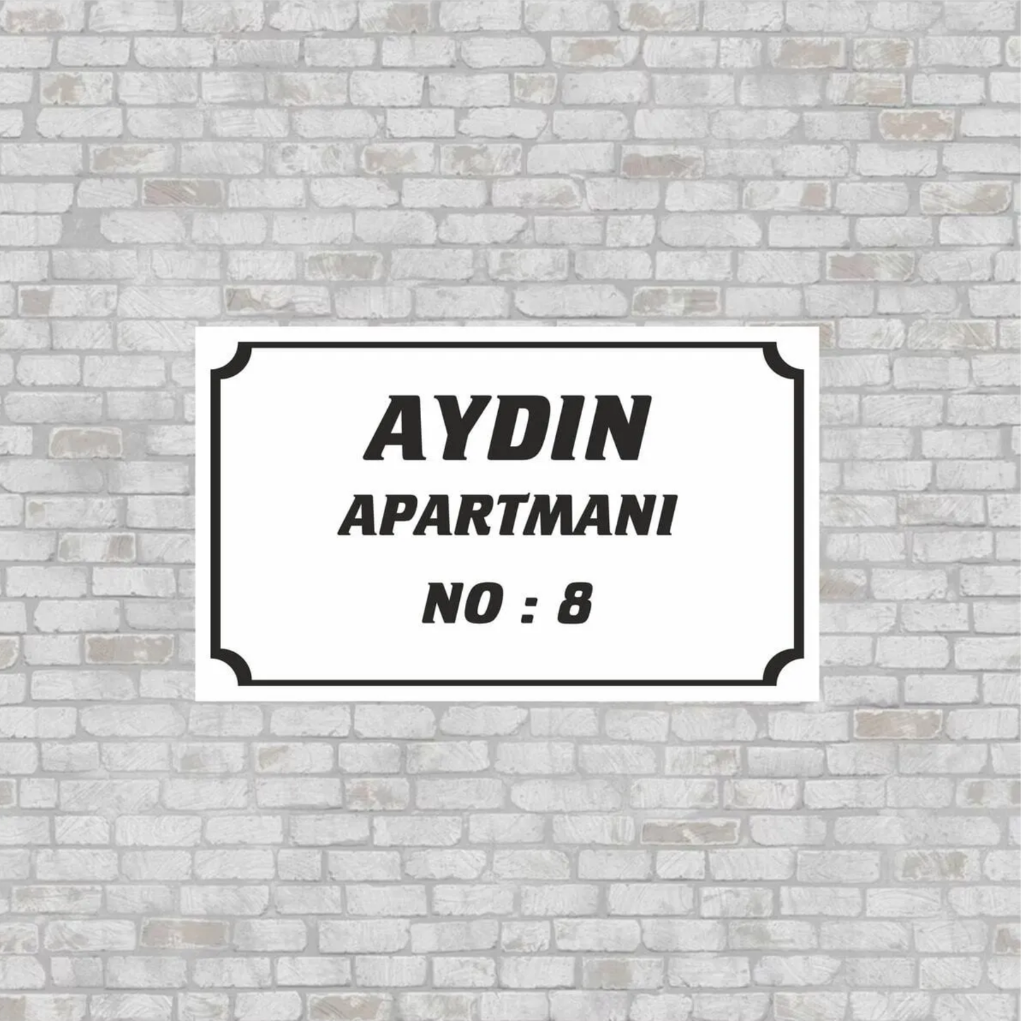 Kişiye özel apartman adı ve numara yazılı beyaz pleksi tabela, tuğla duvar üzerinde lifestyle görseli