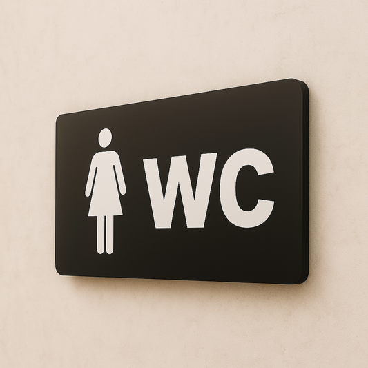 Bayan WC tabelası, siyah metal yüzey, beyaz kadın figürü ve WC yazısı, 22x8 cm